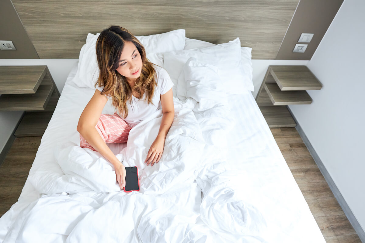 Woman sitting on a bed in a hotel room