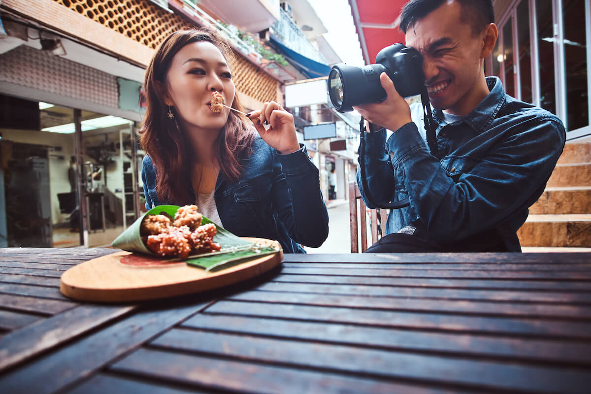Man taking a photo of a girl eating