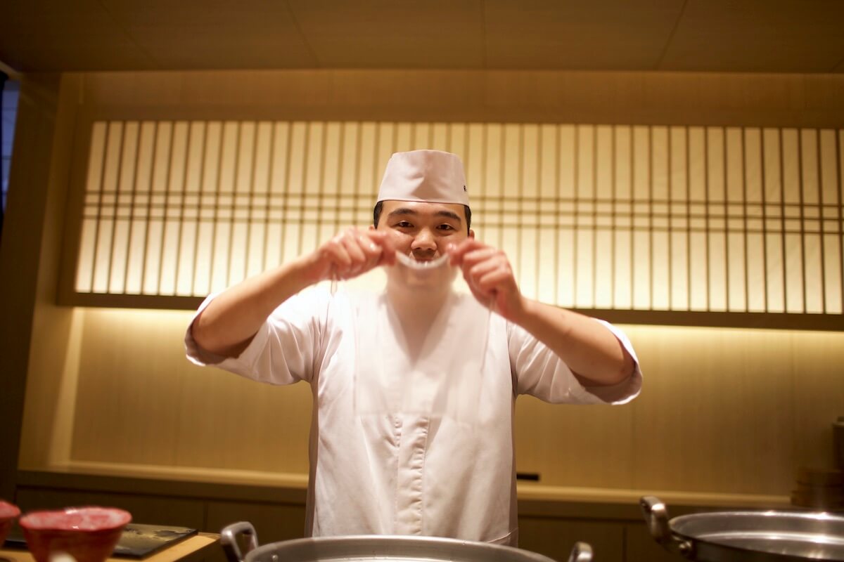 Sushi chef smiling behind a sheet of dessert noodles