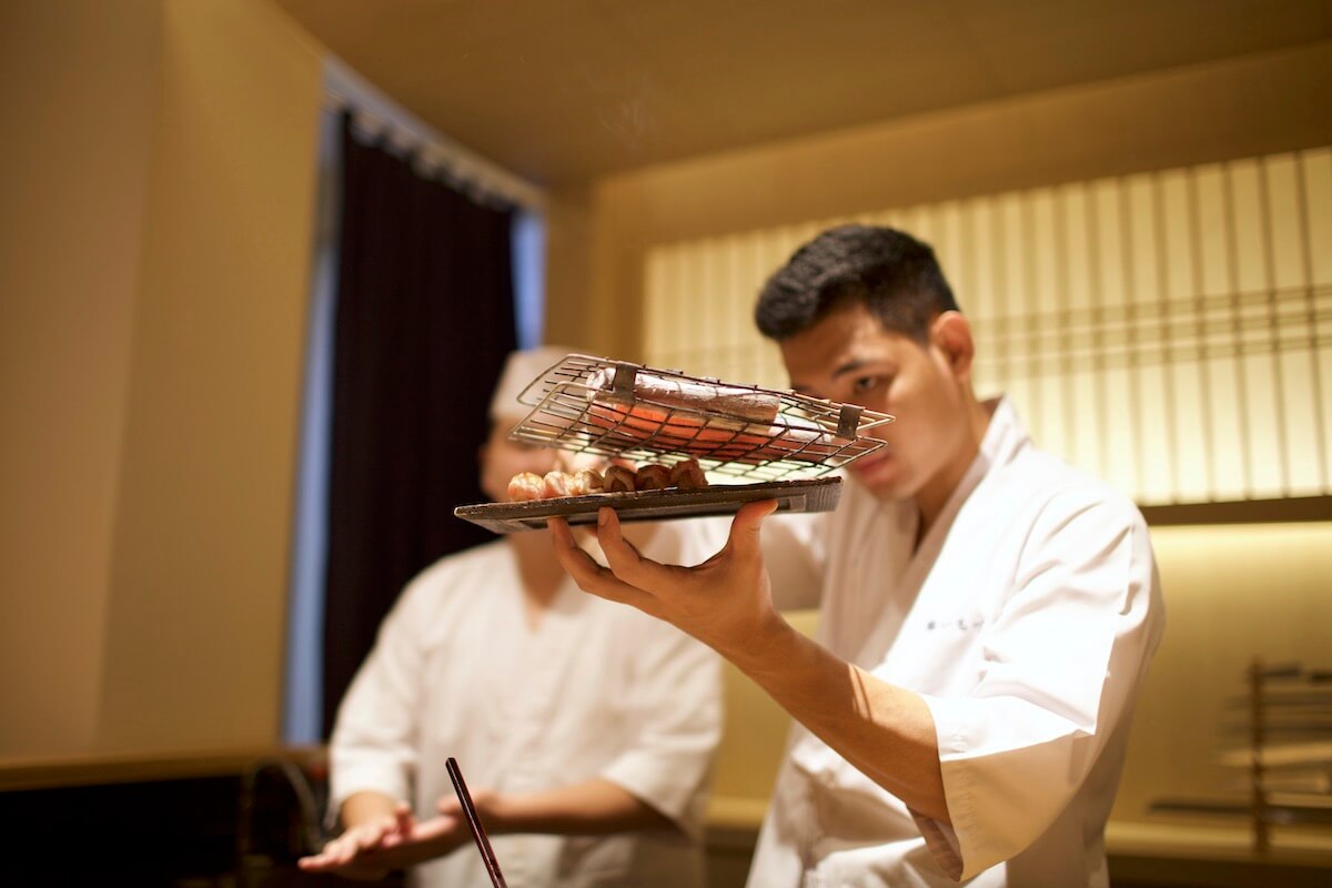 Chef grilling tuna under charcoals