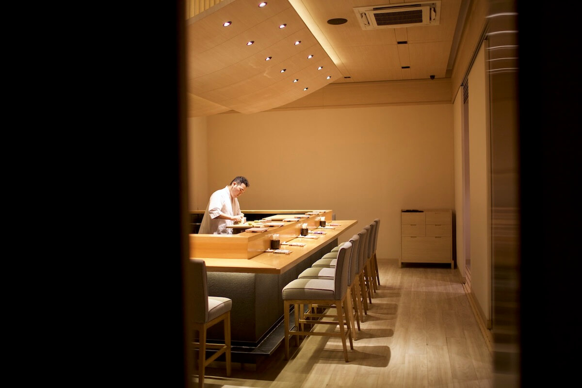 Sushi chef preparing behind counter